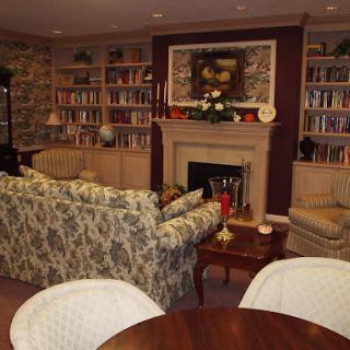 A cozy living room featuring a fireplace, bookshelves filled with books, and comfortable seating.
