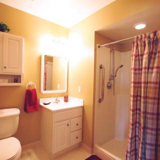 A cozy bathroom featuring a shower, toilet, and sink with warm yellow walls.