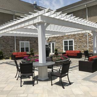 A beautiful patio featuring a white pergola with outdoor seating and tables, perfect for relaxation.