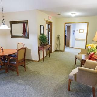 A cozy interior featuring a dining table and chairs, with a seating area adorned with plants and decorative elements.