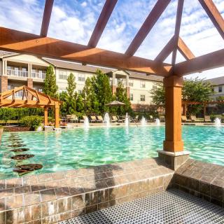 Luxurious apartment complex with a large outdoor pool surrounded by landscaped gardens.