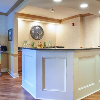 Reception desk area in an office setting with a wall clock and overhead lighting.