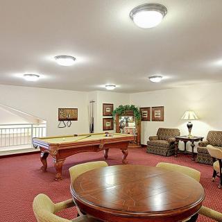 A spacious game room featuring a pool table, comfortable seating, and warm lighting.