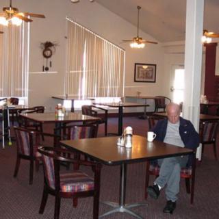 A man sits alone in an empty dining area of a restaurant.