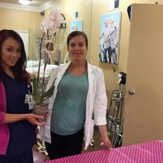 Two healthcare professionals posing in a clinic setting with an orchid.