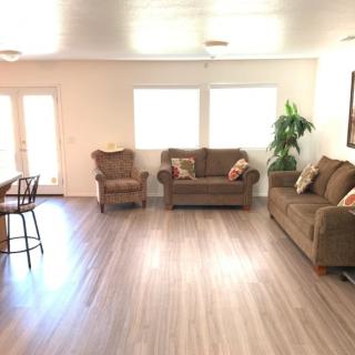 A spacious living room with two sofas, an armchair, and hardwood flooring.