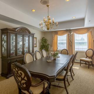 A traditional dining room with a large table, chairs, and a chandelier.