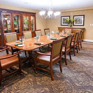 A well-furnished dining room featuring a large table surrounded by chairs, with a decorative chandelier above.