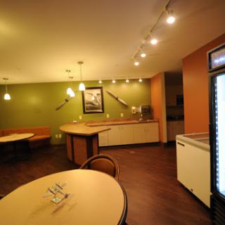 A modern kitchen and dining area featuring green walls, stylish lighting, and minimalistic furniture.