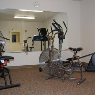 A small gym with various exercise equipment including stationary bikes and an elliptical machine.