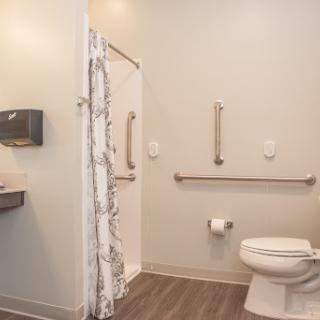 A clean and accessible bathroom featuring a shower, toilet, and sink.