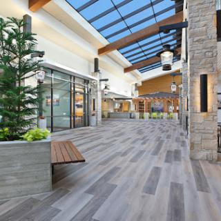 A bright and inviting interior of a modern shopping mall, featuring natural light through a large skylight and stylish design elements.