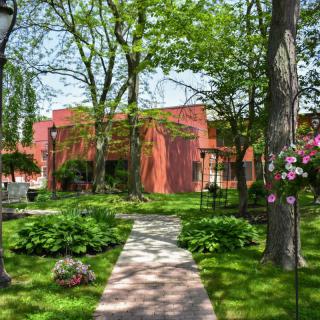 A scenic garden pathway leading to a building surrounded by trees and flowers.