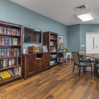 A cozy reading area featuring bookshelves, a table, and chairs on a wooden floor.