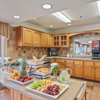 A well-organized kitchen featuring a breakfast buffet with a variety of fresh fruits on the countertop.
