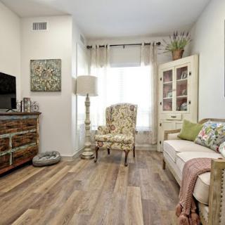 A cozy living room featuring an elegant armchair, a television, and warm wooden flooring.