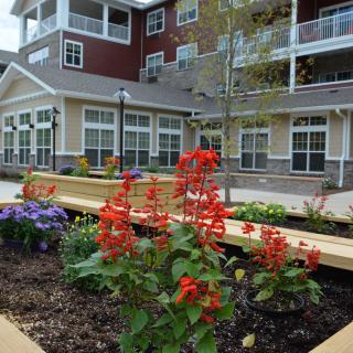 A flower garden in front of a modern apartment building.