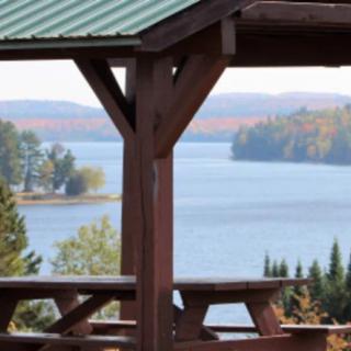 A scenic view of a lake surrounded by trees, framed by a wooden structure.