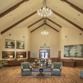 A spacious lobby with elegant chandeliers, wooden beams, and comfortable seating.