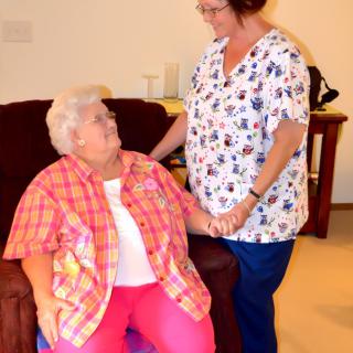 A caregiver providing assistance to an elderly woman in a comfortable setting.
