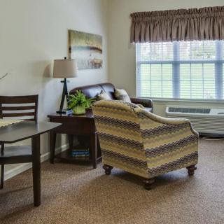 A cozy living room with an armchair, sofa, and a large window.