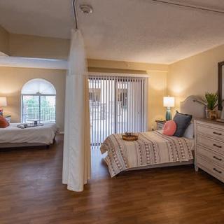 A cozy bedroom with two beds, natural lighting, and wooden flooring.