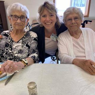 A group photo of three women sitting together at a table, smiling.