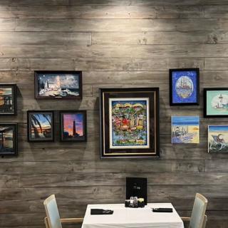 A cozy dining area adorned with a variety of framed paintings on the wall.
