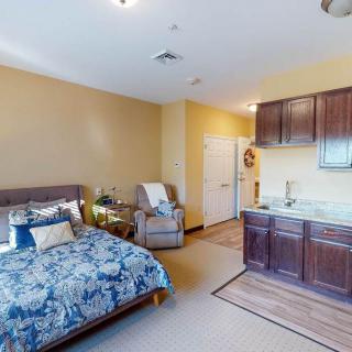 A cozy studio apartment with a neatly arranged bedroom and kitchenette.