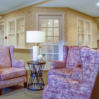 A cozy living room with two patterned armchairs, a small round table, and a lamp.