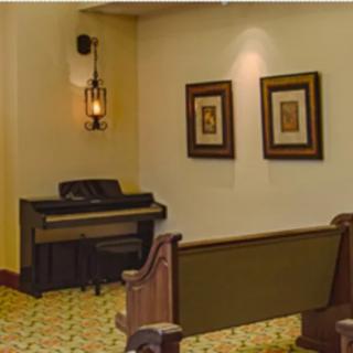 A cozy interior with a piano, church pew, and decorative wall art.