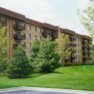 A residential apartment building surrounded by lush greenery and trees.