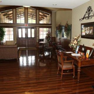 A welcoming reception area featuring elegant wooden flooring, stylish furniture, and ample natural light from large windows.
