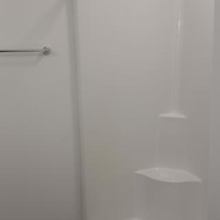 A minimalist bathroom shower with a towel rack.