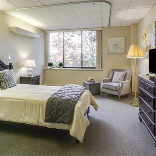 Cozy bedroom with a single bed, armchair, and large window.
