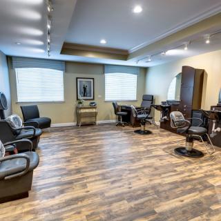 A modern barber shop with stylish chairs and mirrors, featuring warm lighting and wooden flooring.