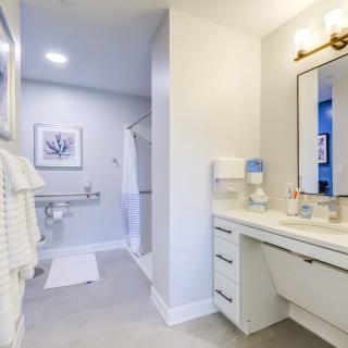 A modern and clean bathroom with white decor, featuring a mirror, sink, and neatly arranged towels.
