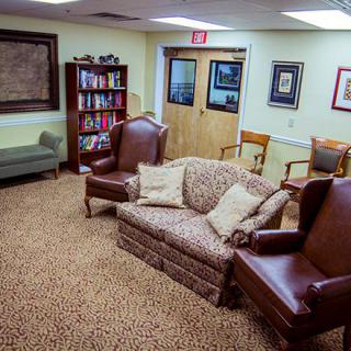 A cozy waiting room with various seating options and a bookshelf.