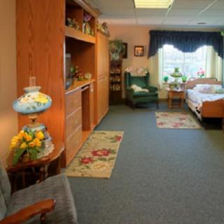 A cozy bedroom with a comfortable armchair, wooden furniture, and a window view.
