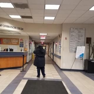A view of a hallway in a public building, featuring an information center and a person walking away.