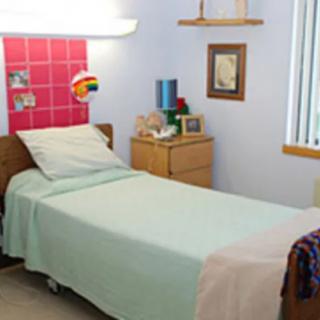 A neatly arranged single bed in a room with a bedside table and decor.