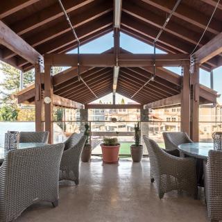 A spacious outdoor dining area with wicker furniture and a wooden roof.