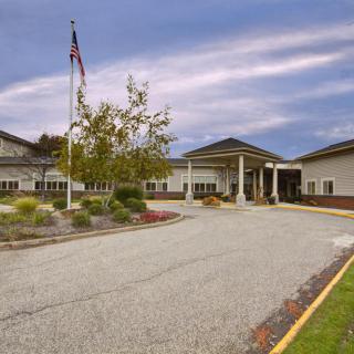 A large building with a driveway and landscaping under a cloudy sky.