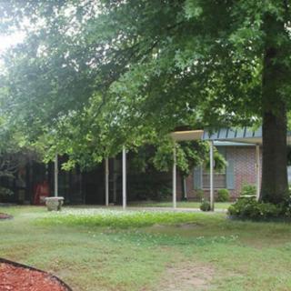 A house with a lush green yard and surrounding trees.