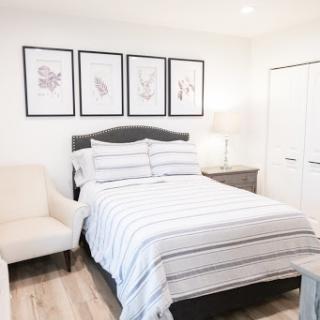 A cozy and stylish bedroom featuring a comfortable bed, contemporary artwork, and minimalist furniture.