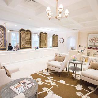 A modern and cozy waiting room with elegant furniture and a chandelier.