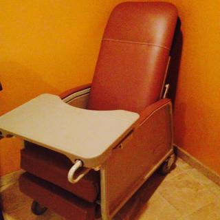 A recliner chair with an attached tray in a room with orange walls.