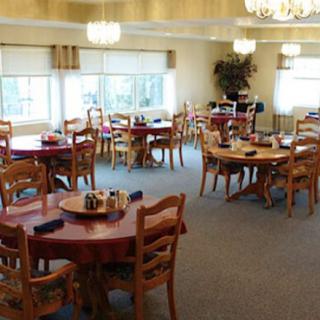 An empty dining area with wooden tables and chairs arranged neatly under soft lighting.