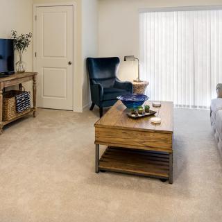 A cozy living room with a coffee table, armchair, television, and a lamp.