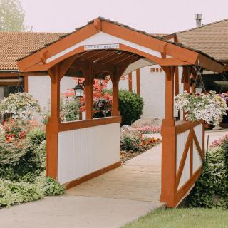 A charming wooden bridge in a landscaped garden, surrounded by vibrant flowers.